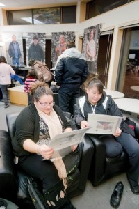 From left, Laura Hendrie and Janelle Pierrot glance through a compilation of photos from the exhibit.