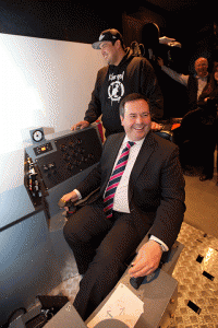 Mine training graduate Conan Zoe (back) coaches federal Employment Minister Jason Kenney on how to use the underground mining simulator at Aurora College in Yellowknife.