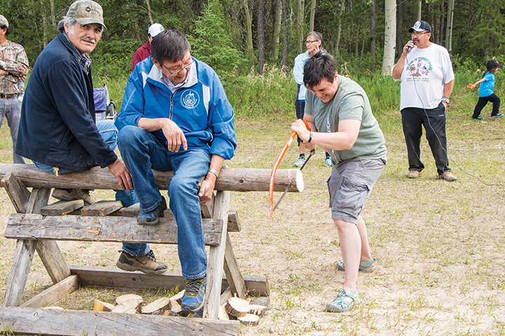 Don Desjarlais and Victor Marie hold the log as Cynthia White shows off her sawing skills.